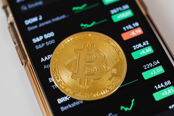 A Bitcoin signage is placed atop the display of crypto currency exchange rates in mobile phone