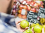 A man compares two apples for quality.